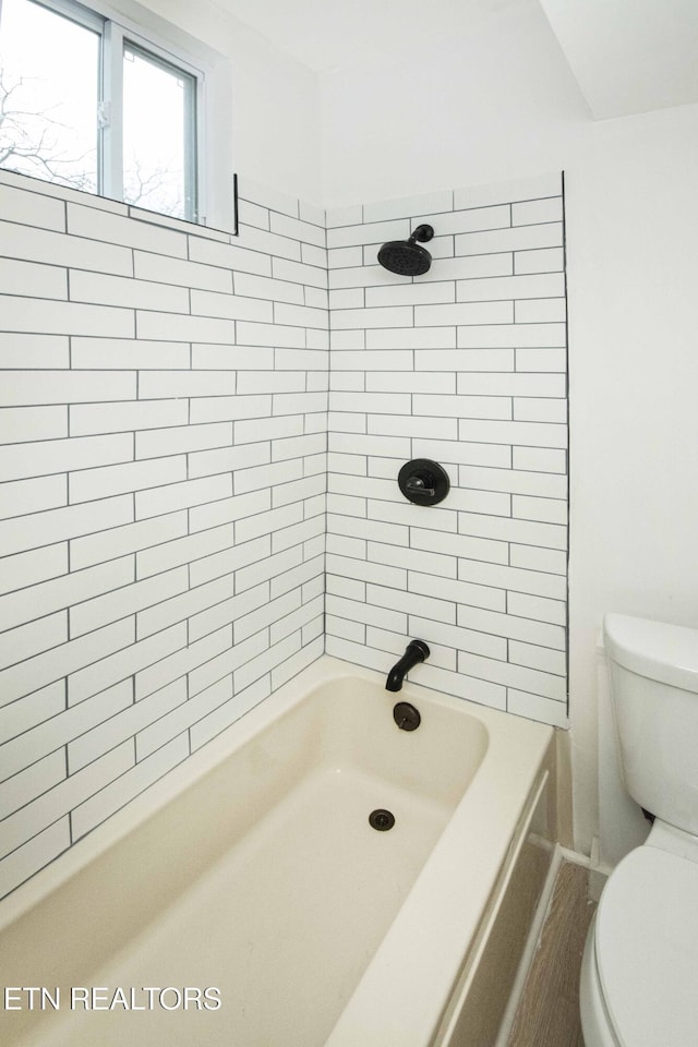 bathroom featuring bathtub / shower combination and toilet