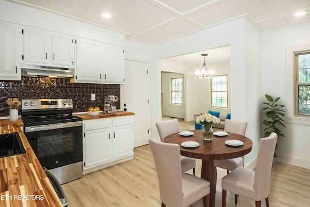 kitchen with light wood-style floors, under cabinet range hood, electric range, and butcher block countertops