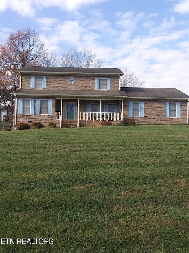 traditional-style home featuring a front yard, brick siding, and a porch