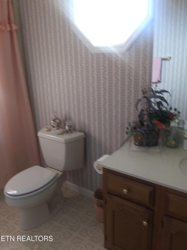 half bathroom featuring tile patterned flooring, vanity, and toilet
