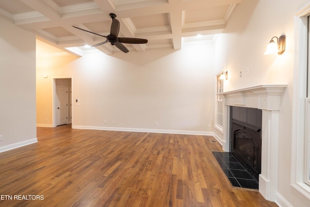 unfurnished living room with beamed ceiling, baseboards, a fireplace, ceiling fan, and wood finished floors