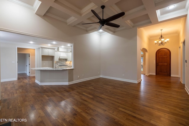 unfurnished living room with dark wood-style flooring, a towering ceiling, arched walkways, and ceiling fan with notable chandelier