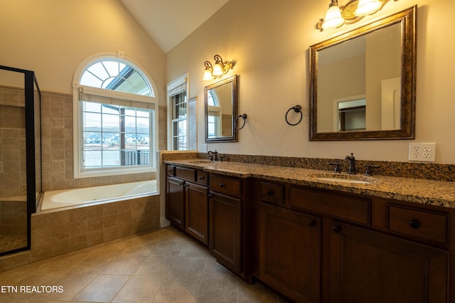 full bath featuring tile patterned floors, vaulted ceiling, double vanity, and a sink