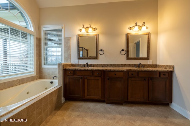 bathroom with double vanity, a sink, a jetted tub, and tile patterned floors