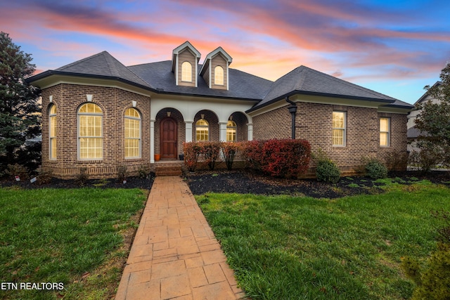 view of front of house with brick siding, a front yard, and a shingled roof