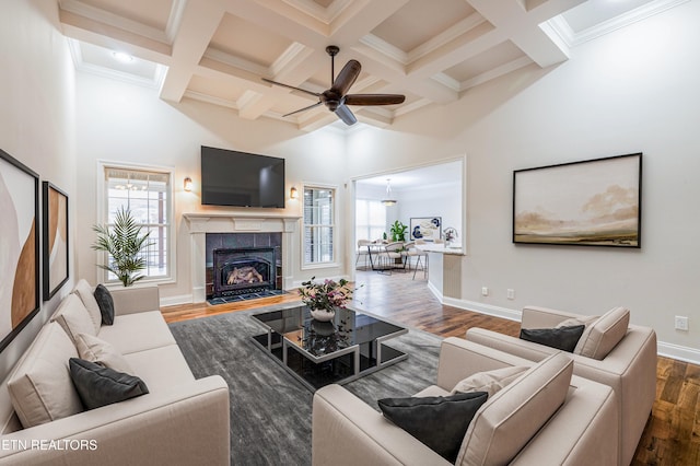 living room with a towering ceiling, plenty of natural light, wood finished floors, and ceiling fan