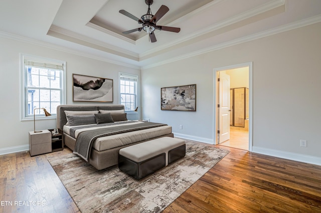 bedroom featuring hardwood / wood-style floors, ornamental molding, baseboards, and a raised ceiling