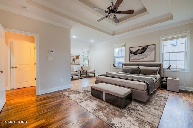 bedroom with hardwood / wood-style floors, baseboards, crown molding, and a raised ceiling