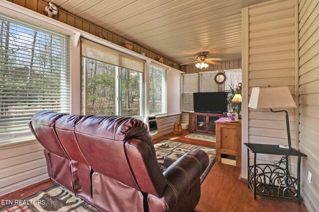living room featuring ceiling fan, wood walls, wood ceiling, wood finished floors, and heating unit