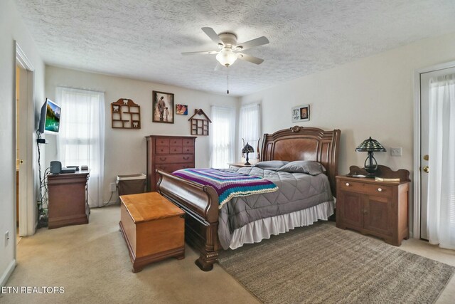 bedroom with light carpet, a textured ceiling, and a ceiling fan