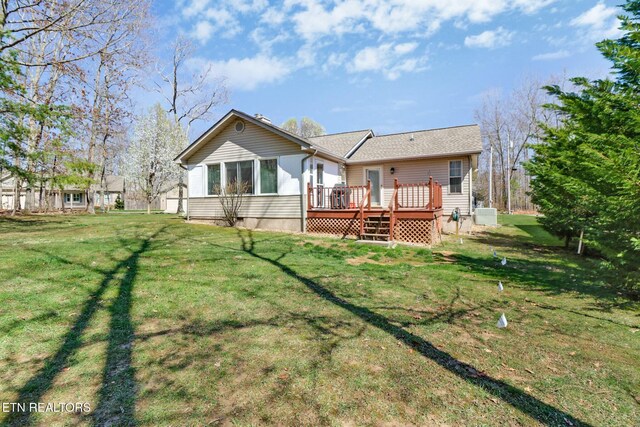 rear view of property featuring a lawn and a wooden deck