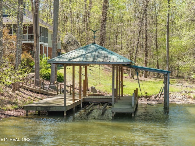 view of dock with a view of trees, a gazebo, and a water view