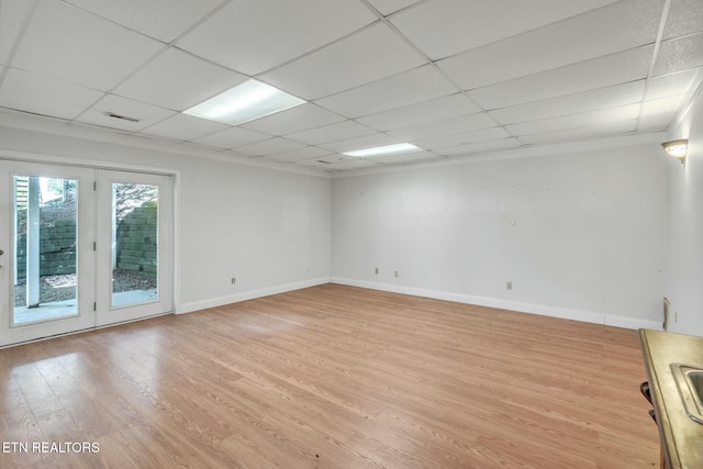 spare room featuring light wood finished floors, a paneled ceiling, baseboards, and visible vents