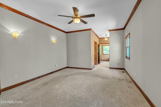 carpeted spare room with baseboards, a ceiling fan, and ornamental molding