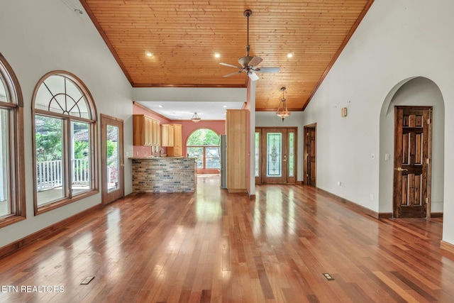 unfurnished living room featuring wooden ceiling, ornamental molding, a ceiling fan, and high vaulted ceiling