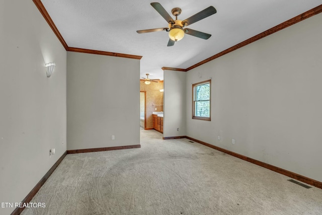 spare room featuring visible vents, baseboards, ceiling fan, carpet, and crown molding