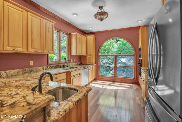 kitchen with light stone countertops, a sink, black appliances, and crown molding