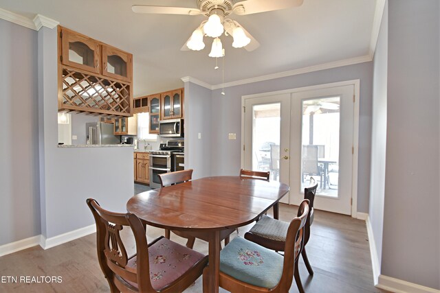 dining room with crown molding, baseboards, a ceiling fan, and french doors
