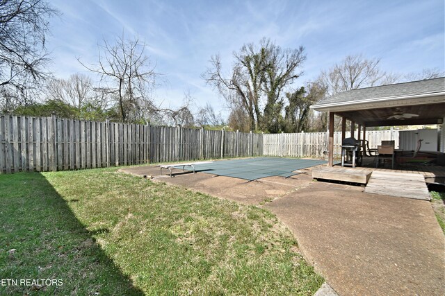 view of swimming pool featuring ceiling fan, a wooden deck, a fenced backyard, a fenced in pool, and a yard