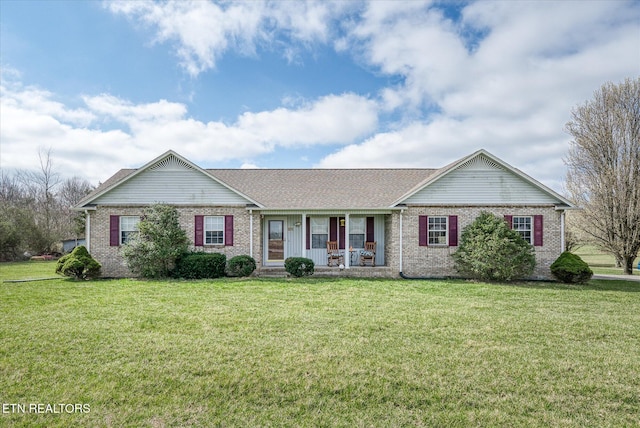 ranch-style home with brick siding, a porch, a front yard, and roof with shingles