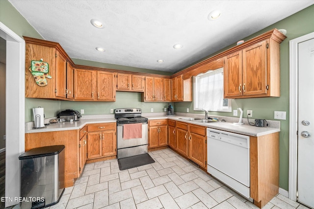 kitchen featuring dishwasher, stainless steel electric range oven, recessed lighting, brown cabinetry, and a sink