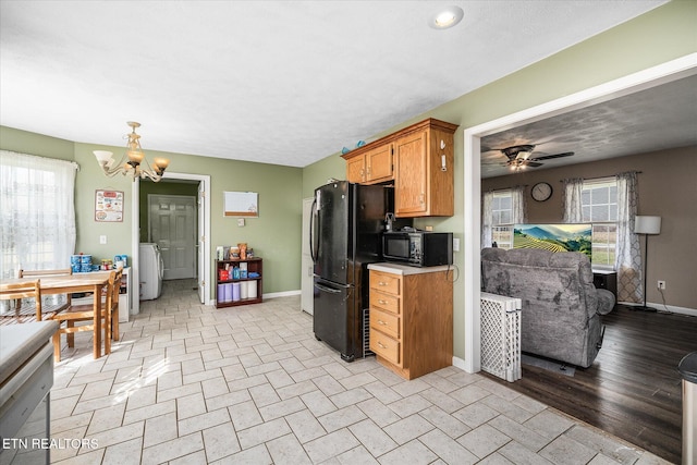 kitchen with baseboards, washer / clothes dryer, black appliances, light countertops, and ceiling fan with notable chandelier