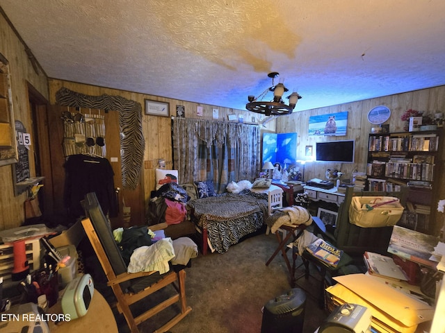 bedroom with a textured ceiling, a notable chandelier, wooden walls, and carpet