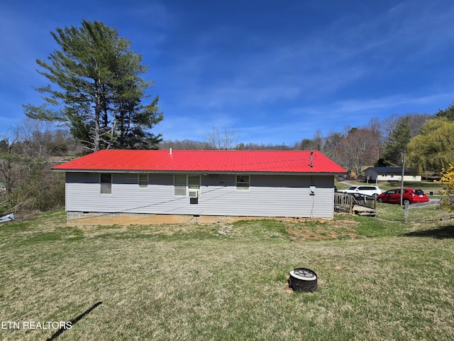 view of side of home featuring a lawn and metal roof