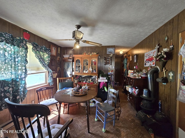 dining room featuring wooden walls, a ceiling fan, and a textured ceiling
