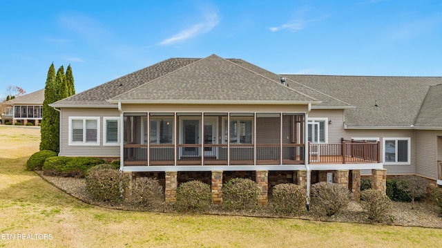 rear view of property featuring a sunroom, a shingled roof, and a yard
