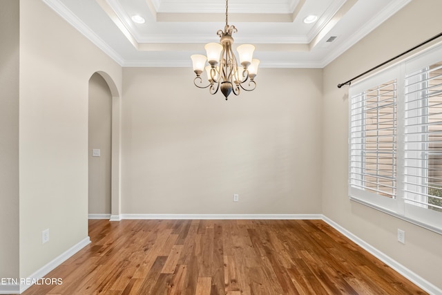 spare room with arched walkways, a tray ceiling, an inviting chandelier, and a wealth of natural light