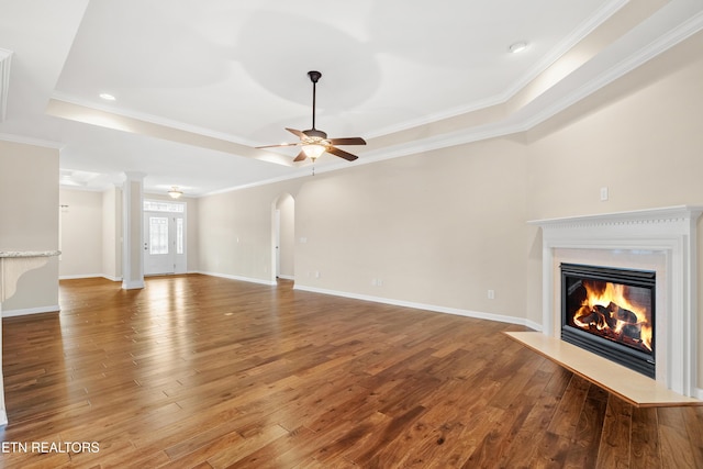 unfurnished living room featuring a fireplace with flush hearth, ceiling fan, ornamental molding, and hardwood / wood-style floors