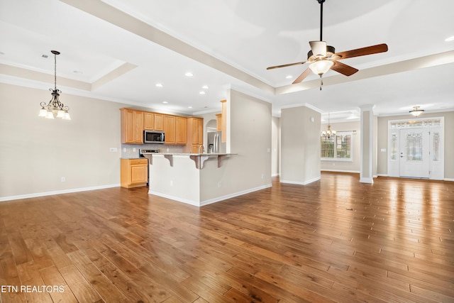 unfurnished living room featuring crown molding, ceiling fan with notable chandelier, baseboards, a raised ceiling, and light wood finished floors
