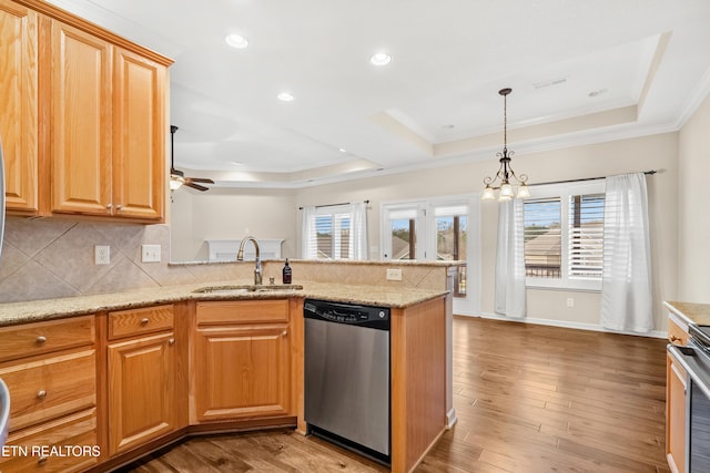 kitchen featuring a peninsula, wood finished floors, a raised ceiling, appliances with stainless steel finishes, and a sink