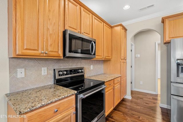 kitchen with stainless steel appliances, backsplash, arched walkways, visible vents, and light stone countertops
