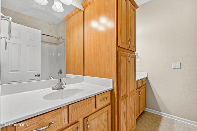 bathroom featuring baseboards, tile patterned floors, a shower, and vanity