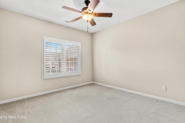 spare room with a ceiling fan, baseboards, light colored carpet, and visible vents