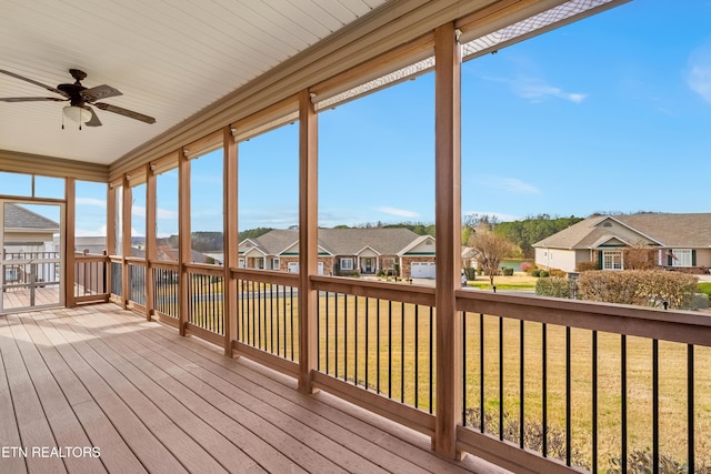 unfurnished sunroom with hardwood / wood-style floors, a residential view, a wooden deck, and ceiling fan