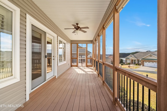 unfurnished sunroom featuring a residential view and a ceiling fan