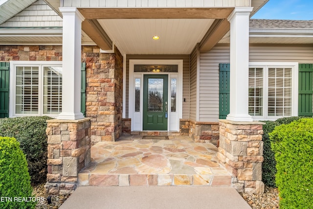 property entrance with stone siding, roof with shingles, and covered porch