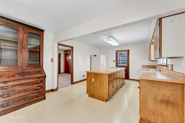 kitchen with a sink, a kitchen island, light countertops, and white fridge with ice dispenser