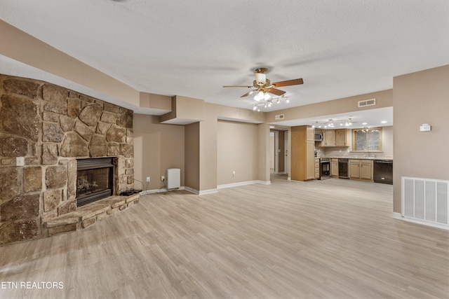 221 Woodland Rd Unit 315, Gatlinburg, TN 37738 - unfurnished living room featuring visible vents, a stone fireplace, a ceiling fan, and light wood-style floors