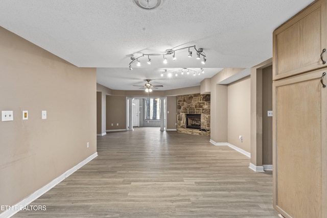 221 Woodland Rd Unit 315, Gatlinburg, TN 37738 - unfurnished living room with light wood-type flooring, ceiling fan, baseboards, and a stone fireplace