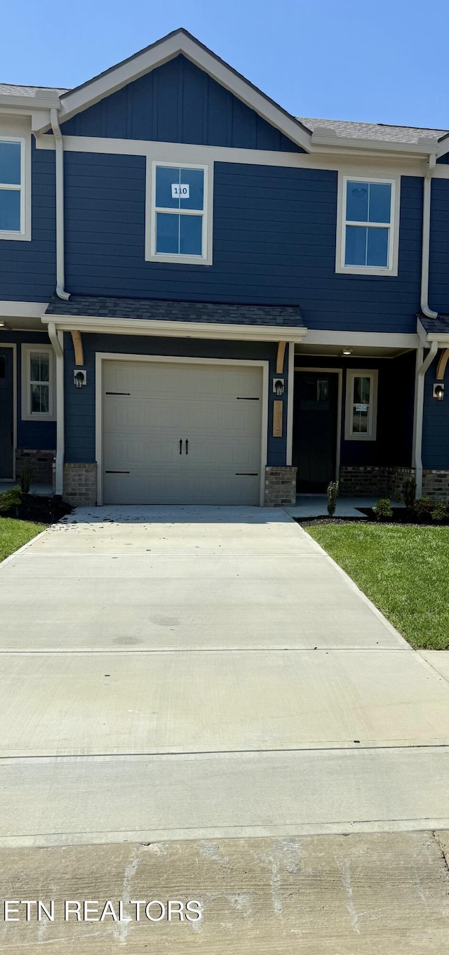 view of front of property with concrete driveway, brick siding, board and batten siding, and a garage