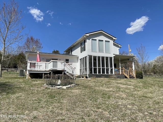 back of property with a wooden deck, fence, a yard, and a sunroom