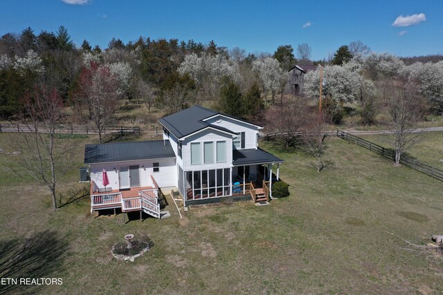 rear view of house with fence, a wooden deck, metal roof, a yard, and a sunroom