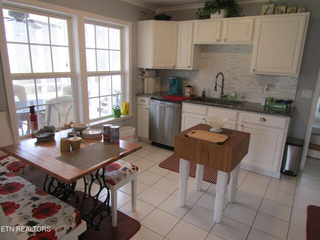 kitchen featuring light tile patterned floors, white cabinetry, a sink, stainless steel dishwasher, and tasteful backsplash