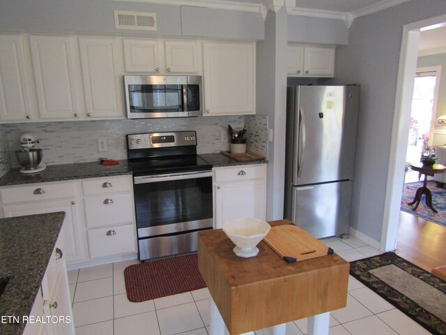 kitchen featuring visible vents, light tile patterned flooring, stainless steel appliances, crown molding, and tasteful backsplash