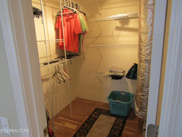 walk in closet with wood finished floors