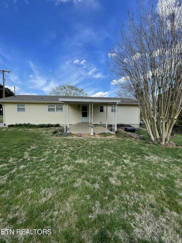 rear view of house with a lawn and a patio